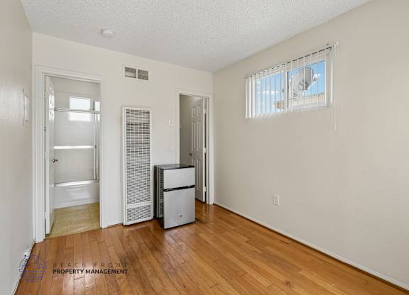 A room with a wooden floor and a window with blinds.
