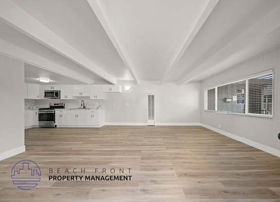 A spacious kitchen with wooden floors and white walls.