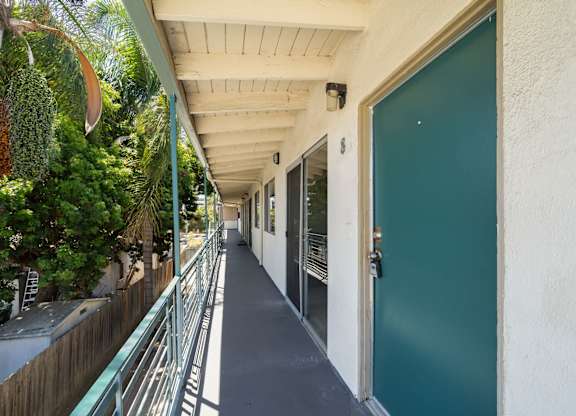 A long, narrow hallway with a green door at the end.