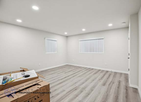 A room with wooden flooring and white walls, with a cardboard box on the floor.