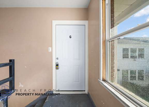A white door with a black handle is in a room with a window.