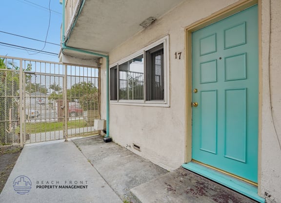 A blue door is on the front of a house with a sign that says Beach Front Property Management.