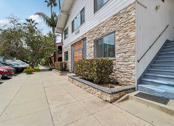 A house with a stone wall and a staircase leading to the entrance.