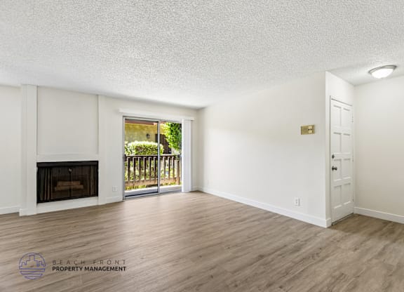 A spacious room with a fireplace and sliding glass doors leading to a balcony.