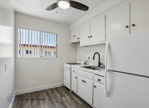 A white kitchen with a fan on the ceiling.