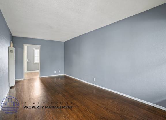 A room with wooden floors and a doorway leading to another room.