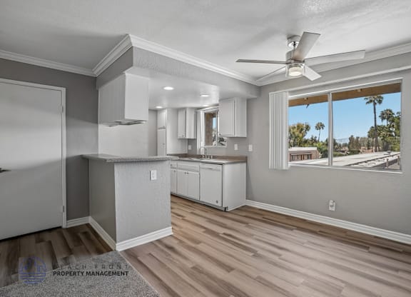 A well-lit kitchen with a ceiling fan and a view of the outdoors through a window.