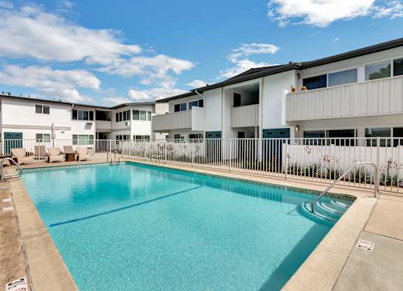 A large swimming pool in front of a white building.