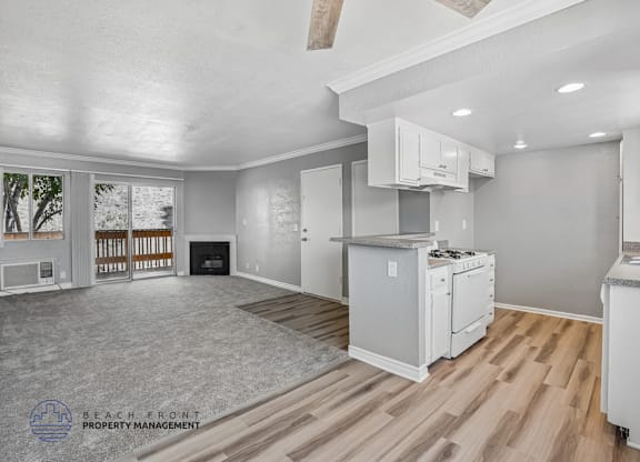 A spacious living room with a fireplace and a kitchen area with white appliances.