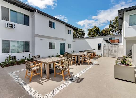 A patio with a table and chairs is surrounded by a white and black patterned rug.