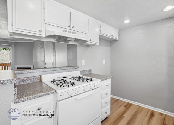 A kitchen with white cabinets and a stove top oven.