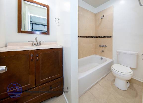 A bathroom with a sink, mirror, toilet and bathtub.