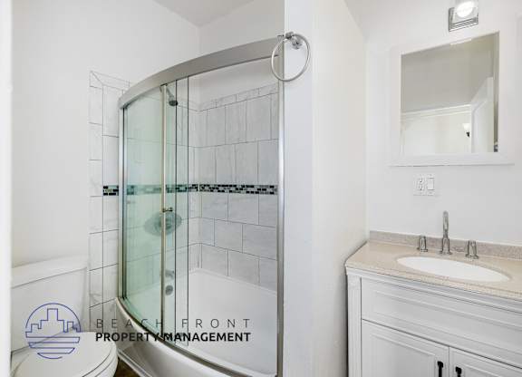 A bathroom with a white sink and a glass shower door.