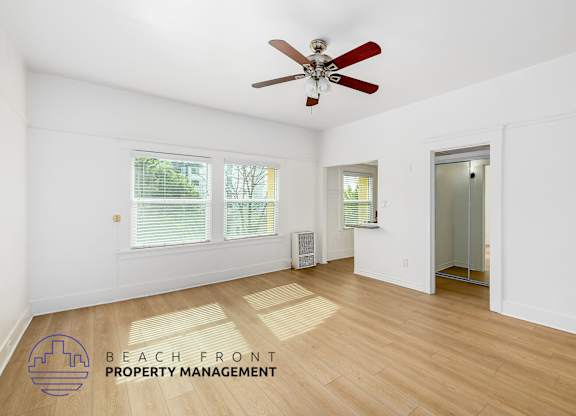 A room with a ceiling fan and wooden flooring.