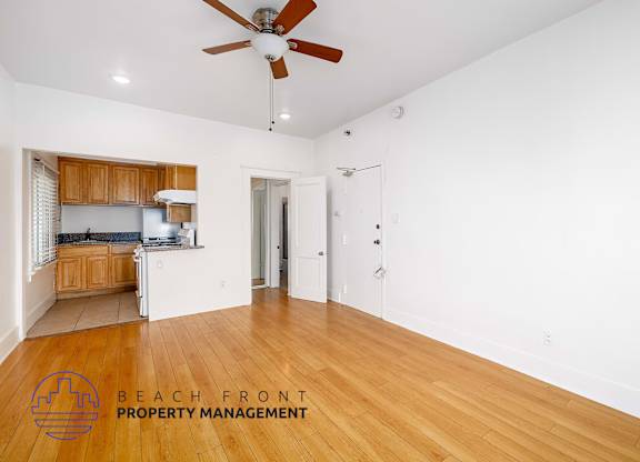 A spacious room with a ceiling fan and wooden flooring.