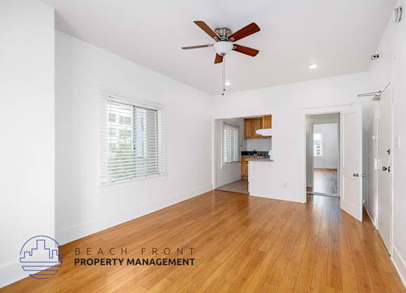 A spacious room with wooden floors and a ceiling fan.