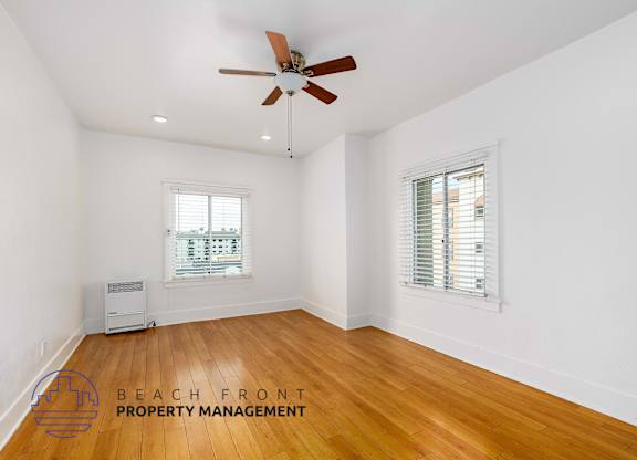 A room with a ceiling fan and wooden flooring.