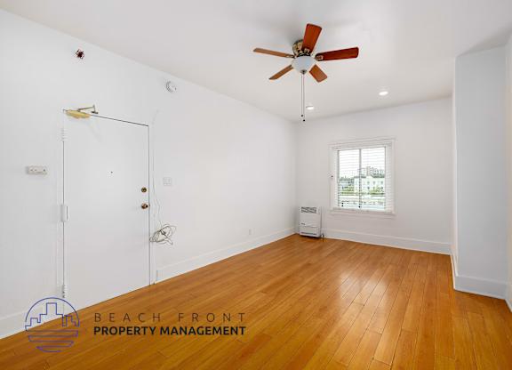 A room with a ceiling fan and wooden floors.