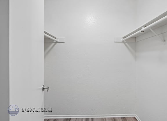 A white closet with a shelf and a logo for Beach Front Property Management.