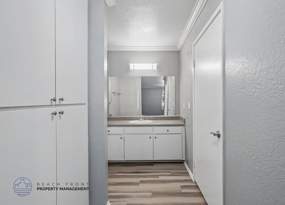 A white bathroom with a mirror and wooden floors.