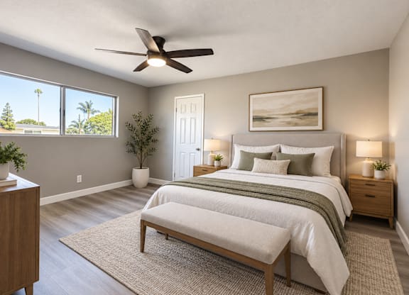 A bedroom with a large bed, a bench, and a ceiling fan.