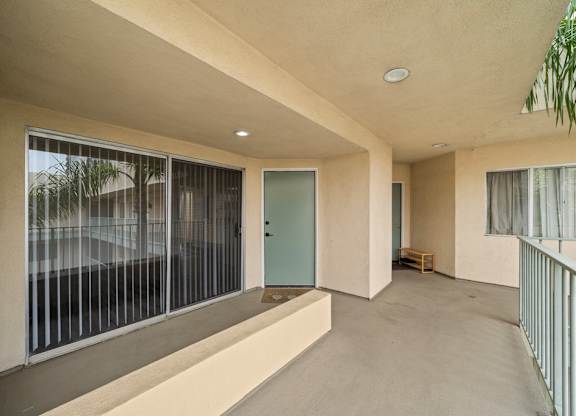 A balcony with a green door and a bench inside a room.
