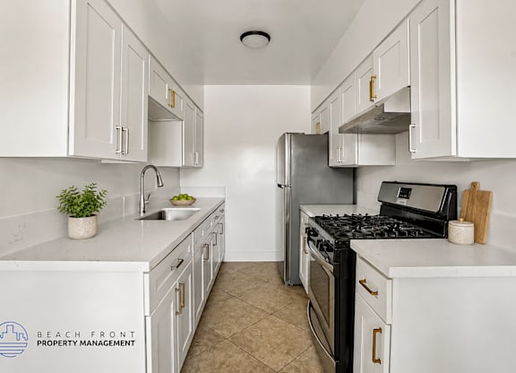 A kitchen with white cabinets and appliances, a sink, and a stove top oven.