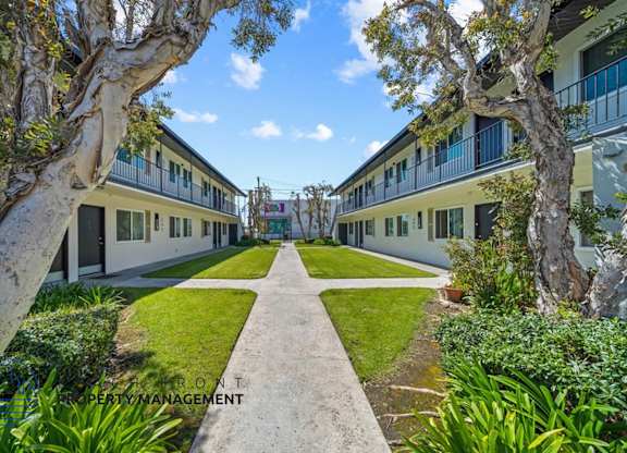 a courtyard between two buildings with grass and trees