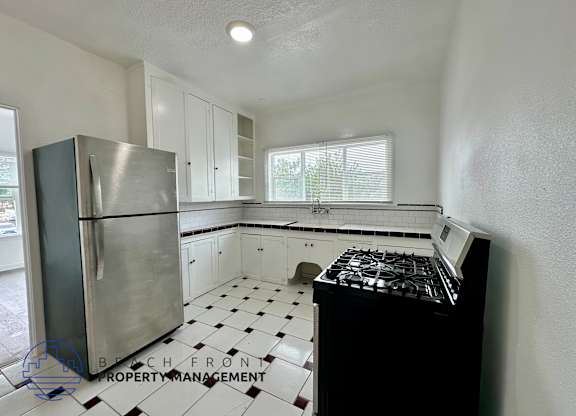 A kitchen with a stove, refrigerator, and cabinets.