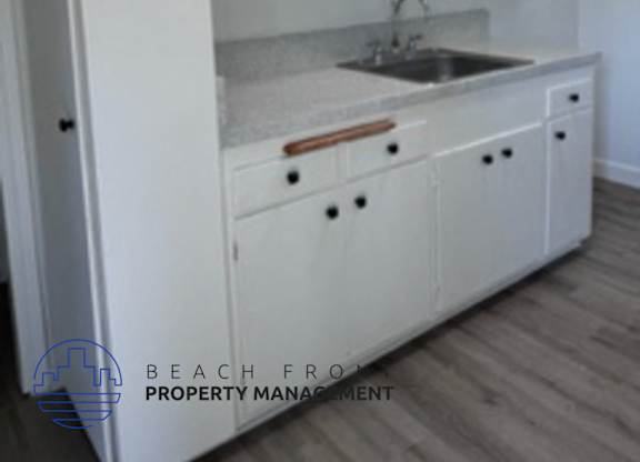 A kitchen with white cabinets and a sink.