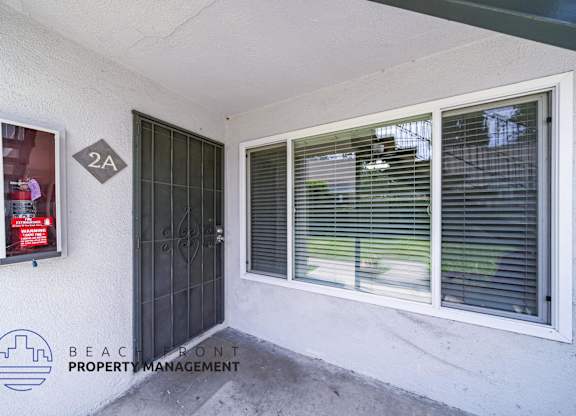 A white wall with a window and a door with a sign on it.