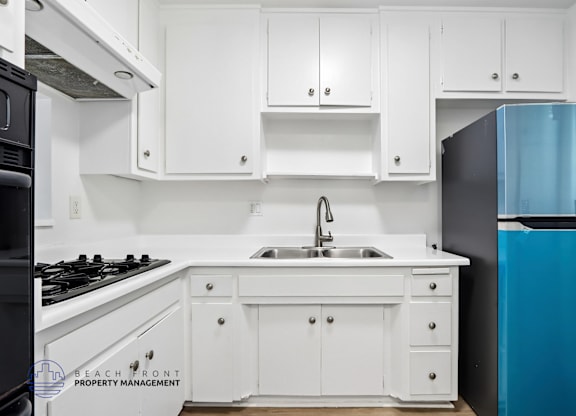 A kitchen with white cabinets and a black stove top.