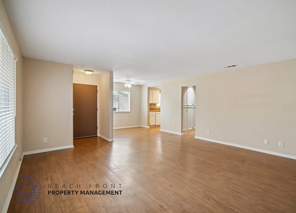 A spacious empty room with wooden floors and white walls.