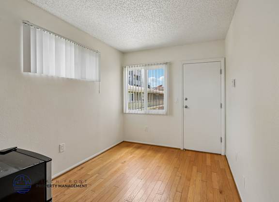 A room with a wooden floor and a window with blinds.
