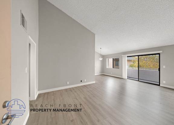 the living room and dining room of an apartment with wood flooring and a balcony