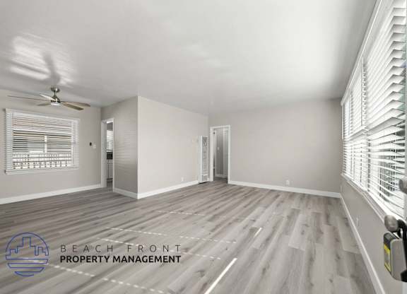A spacious room with wooden flooring and a ceiling fan.