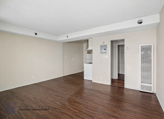 A spacious room with wooden floors and white walls.