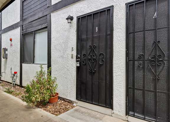 A black gate with a decorative design is on the right side of a white building.