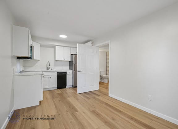 A kitchen with white cabinets and a wooden floor.