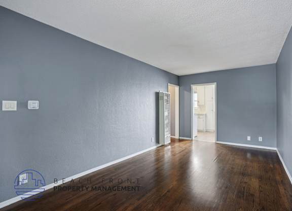 A spacious room with wooden floors and a white ceiling.