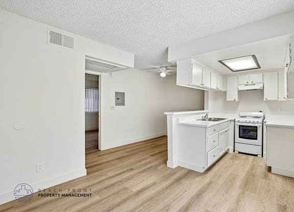 A kitchen with white cabinets and a wooden floor.