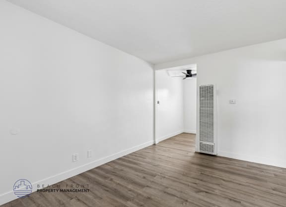A spacious room with wooden flooring and a ceiling fan.