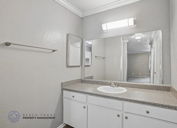 A bathroom with a sink, mirror, and cabinets.