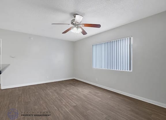 A room with a ceiling fan and a window with blinds.