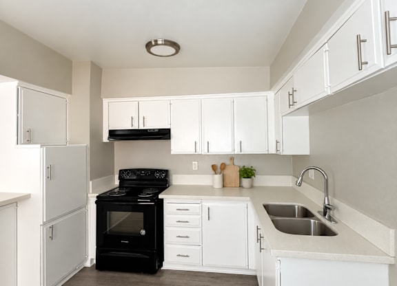 A black stove in a white kitchen with a sink.
