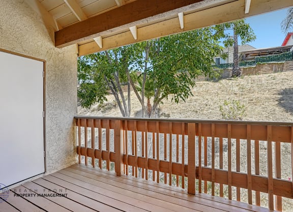 A balcony with a white door and wooden railing.