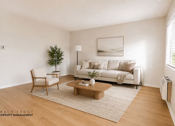 A living room with a white couch, a wooden chair, a coffee table, and a plant.