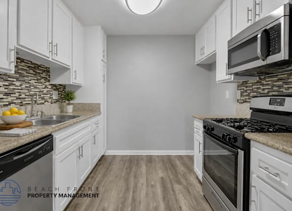 A kitchen with white cabinets and a stone backsplash.