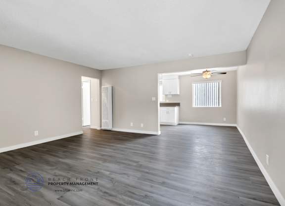 A spacious room with wooden flooring and a large window.