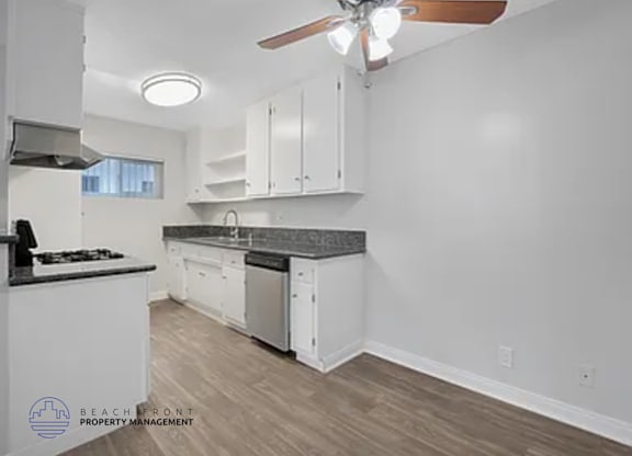 A kitchen with white cabinets and a black countertop.